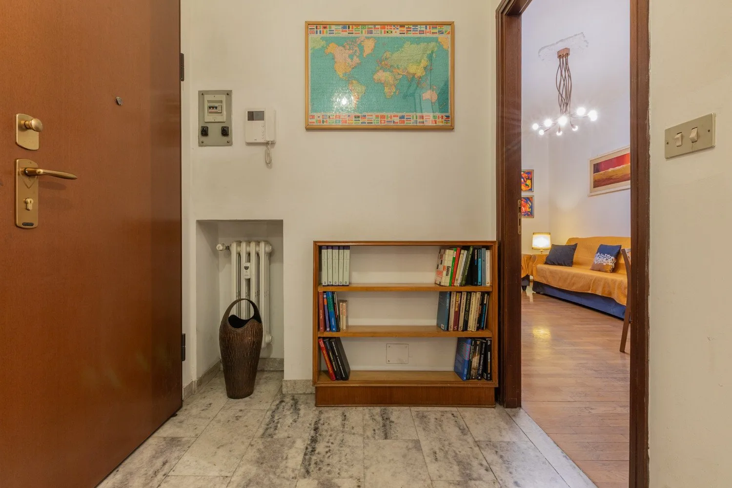 A hallway with a low bookcase and a view into a bedroom.