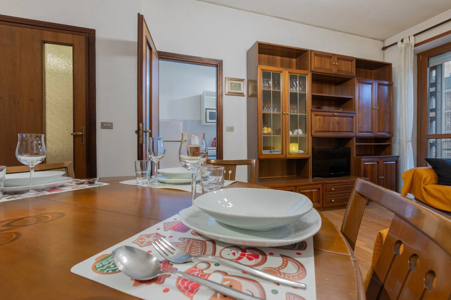 A dining area with a set table and a wooden cabinet along the wall.