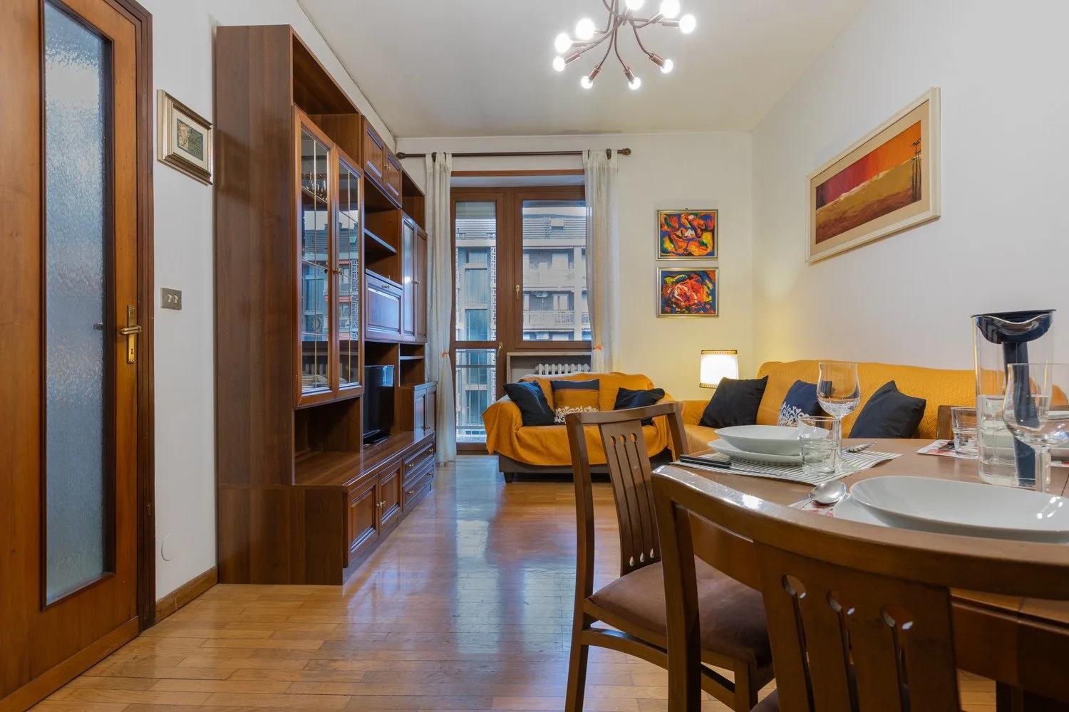 A dining area with a wooden table and chairs beside a living space.
