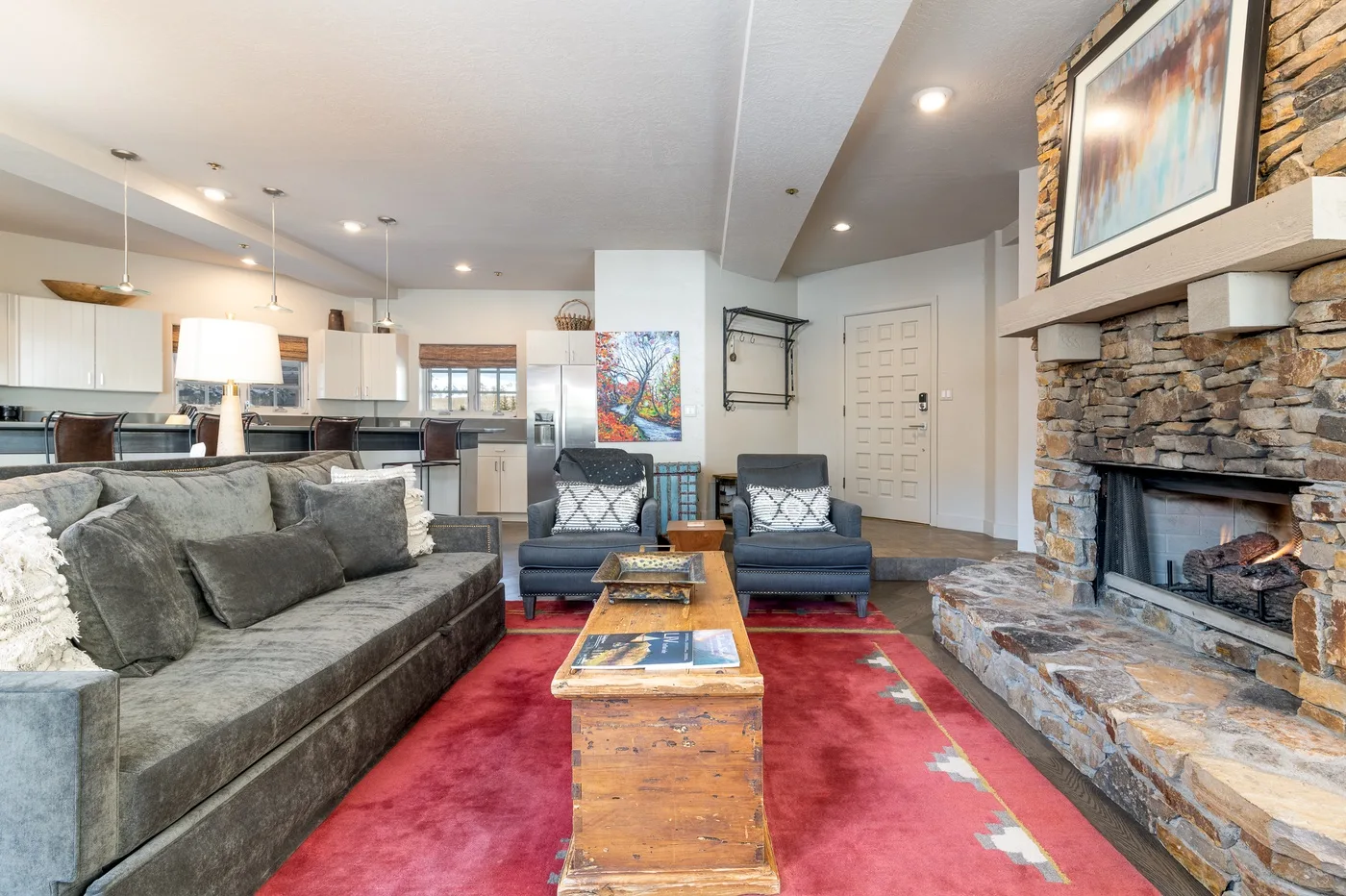 A living room with seating around a coffee table and a stone fireplace.