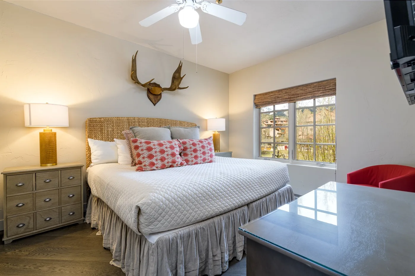 A bedroom with a large bed, bedside lamps, and a window overlooking trees.