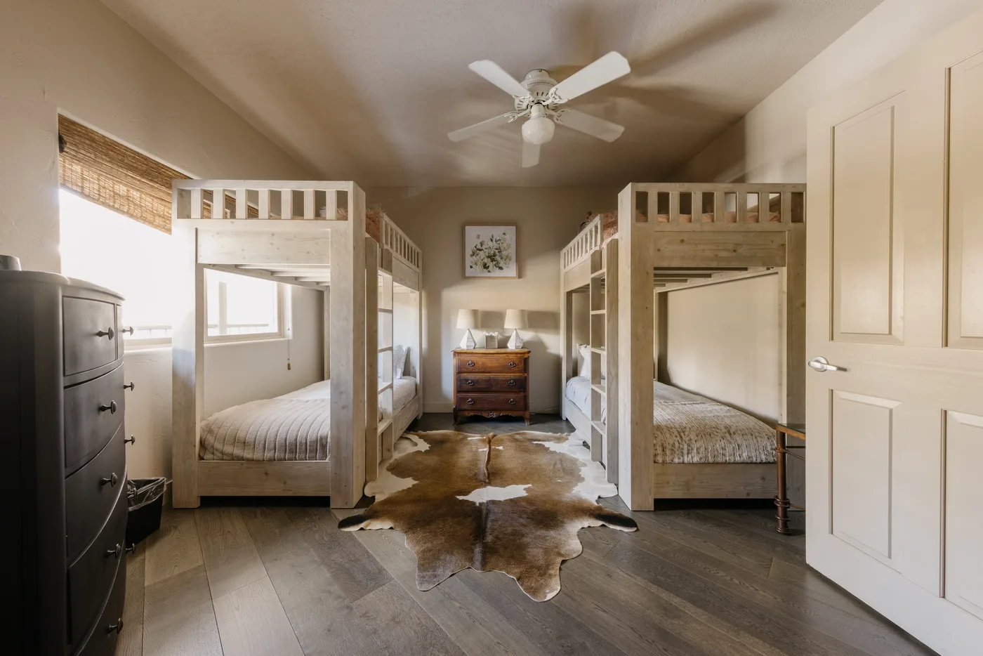 A bedroom with two bunk beds, a ceiling fan, and a hide rug.