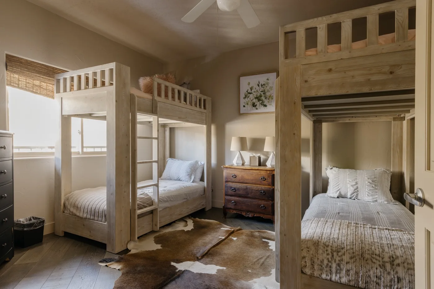 A bedroom with several wooden bunk beds and a dresser.