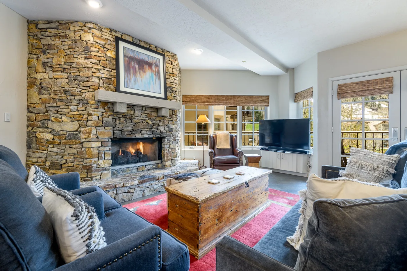 Sala de estar con chimenea de piedra, asientos y una mesa de centro de madera.