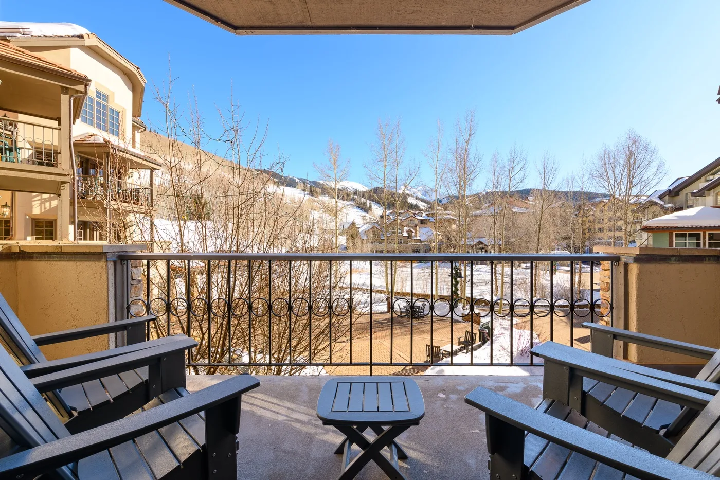 A balcony seating area overlooks snow-dusted trees and nearby buildings.