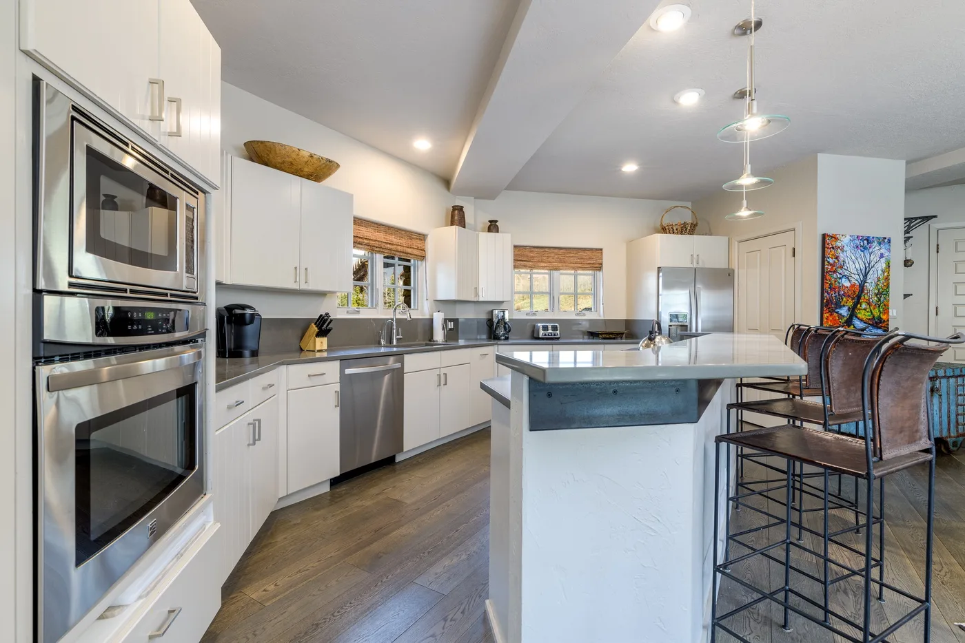 A bright kitchen with a central island, stainless steel appliances, and bar seating.