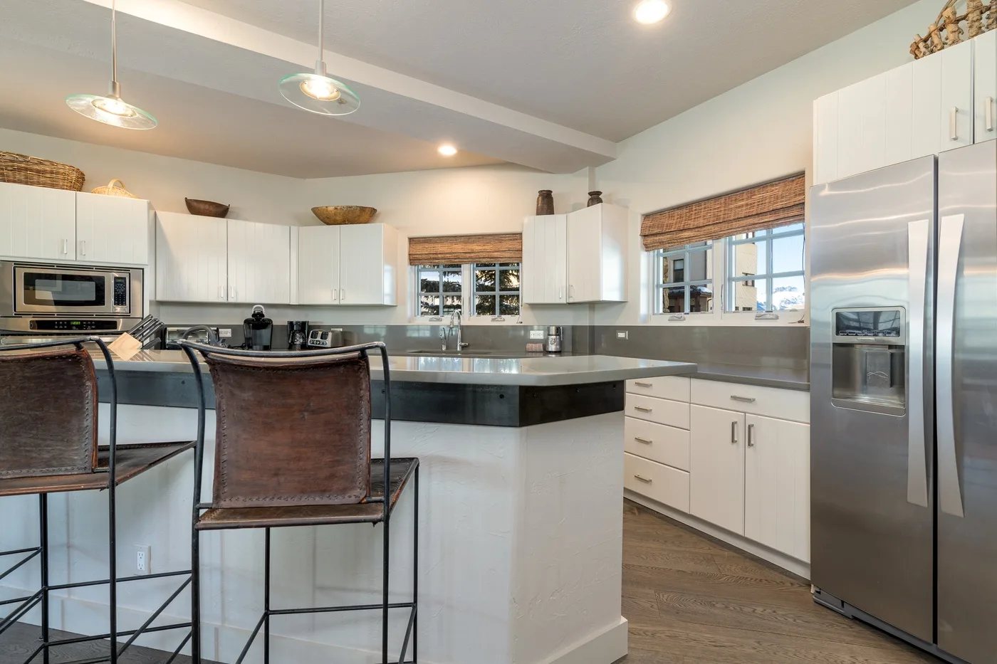 A bright kitchen with white cabinets, a central island, and stainless steel appliances.