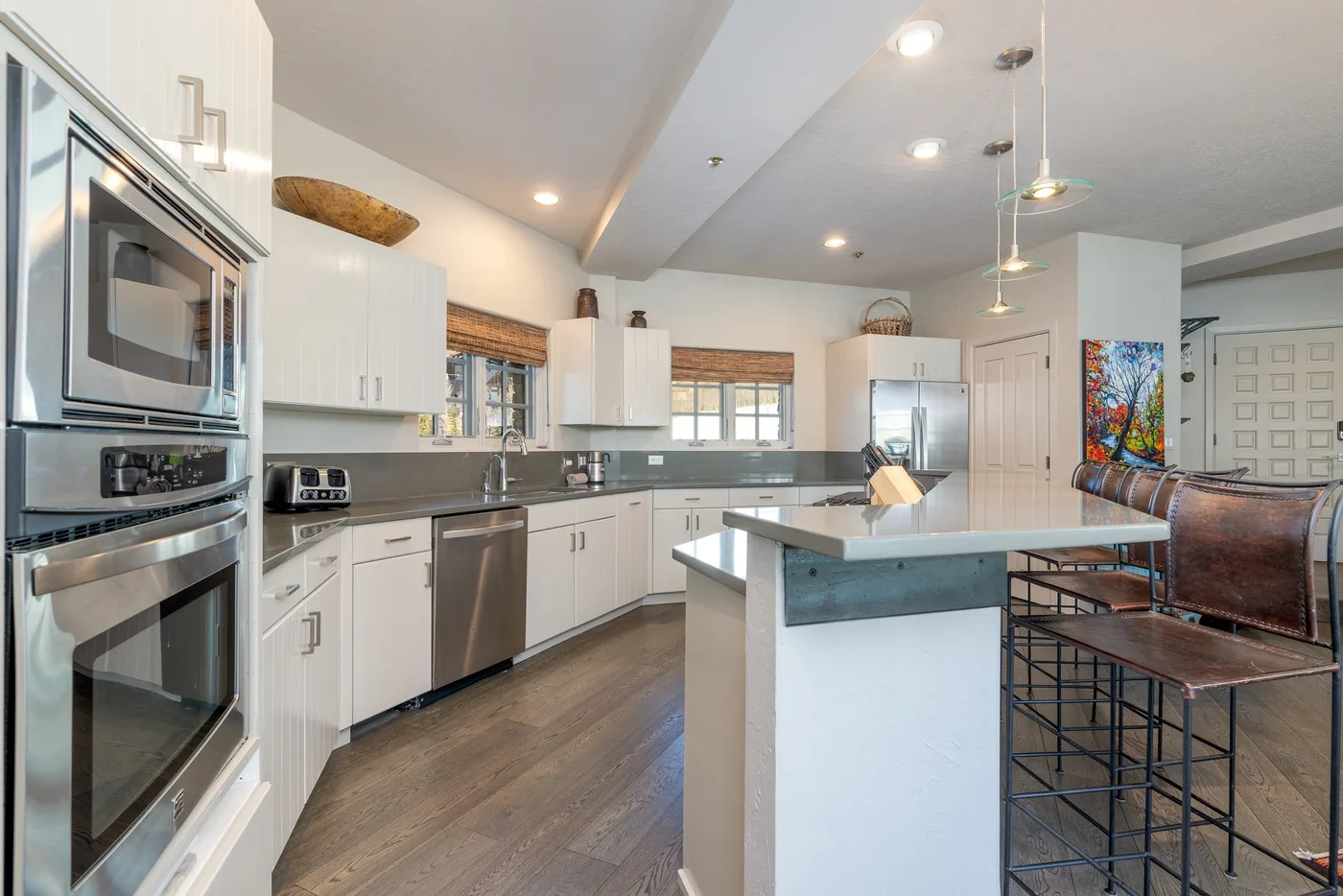 A bright kitchen with white cabinetry, stainless steel appliances, and a central island.
