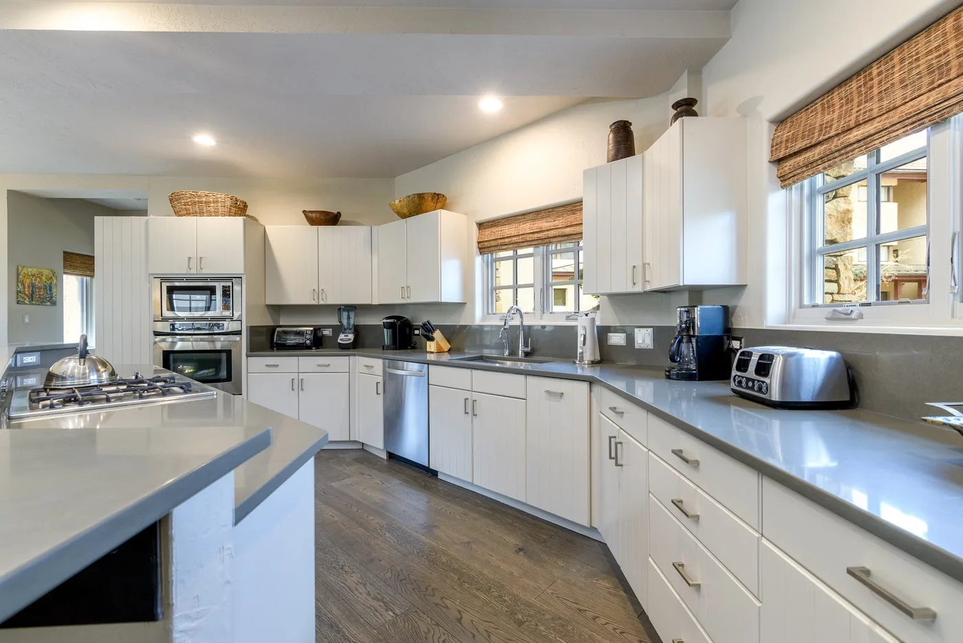 A bright kitchen with white cabinets, dark countertops, and stainless steel appliances.