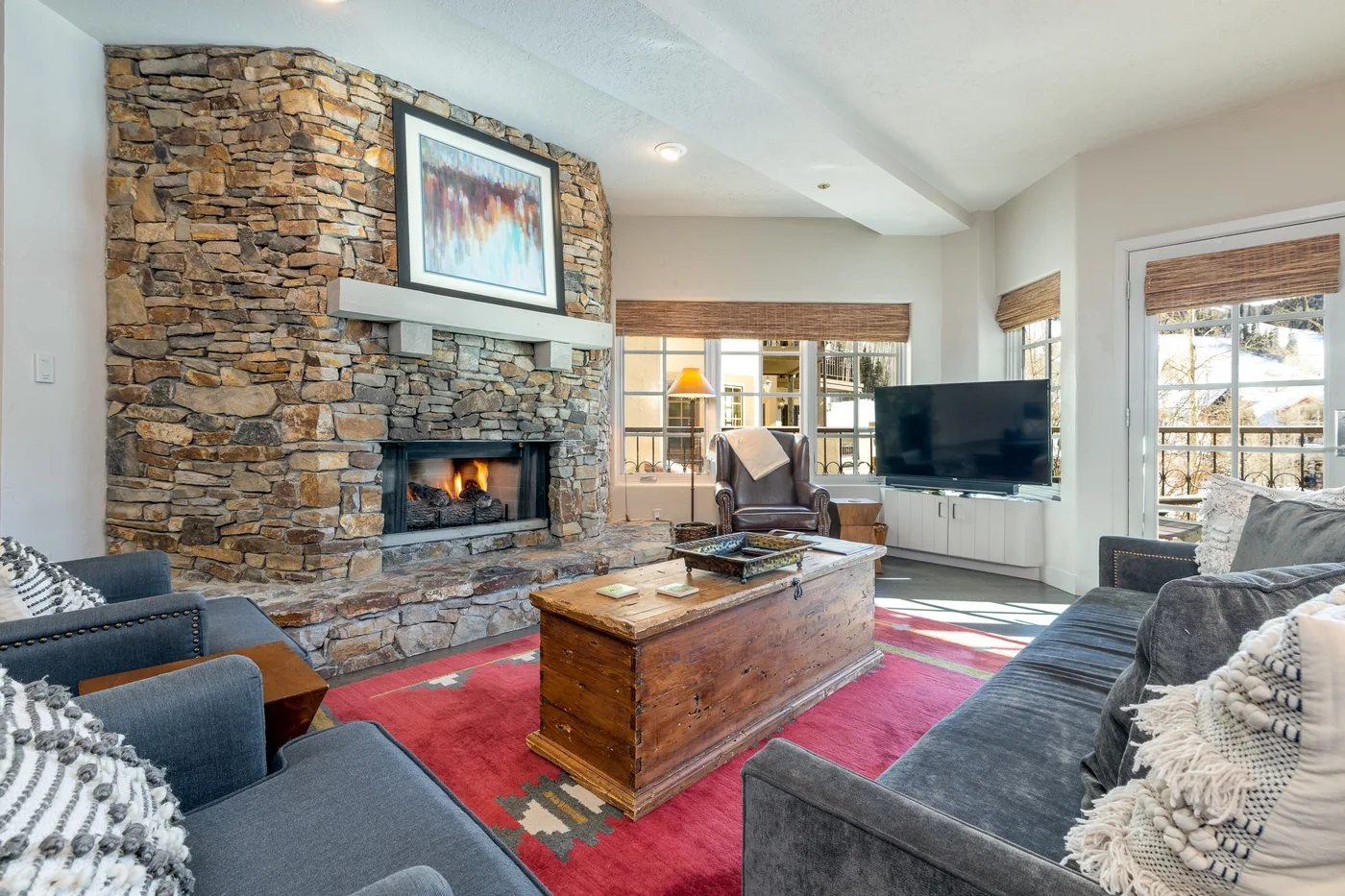 Sala de estar con chimenea de piedra, asientos y una mesa de centro de madera.
