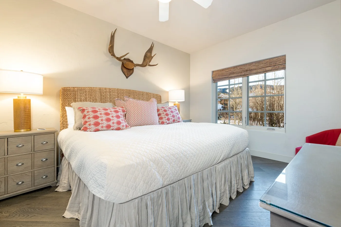 Bedroom with a large bed, bedside lamps, and a window with a woven shade.