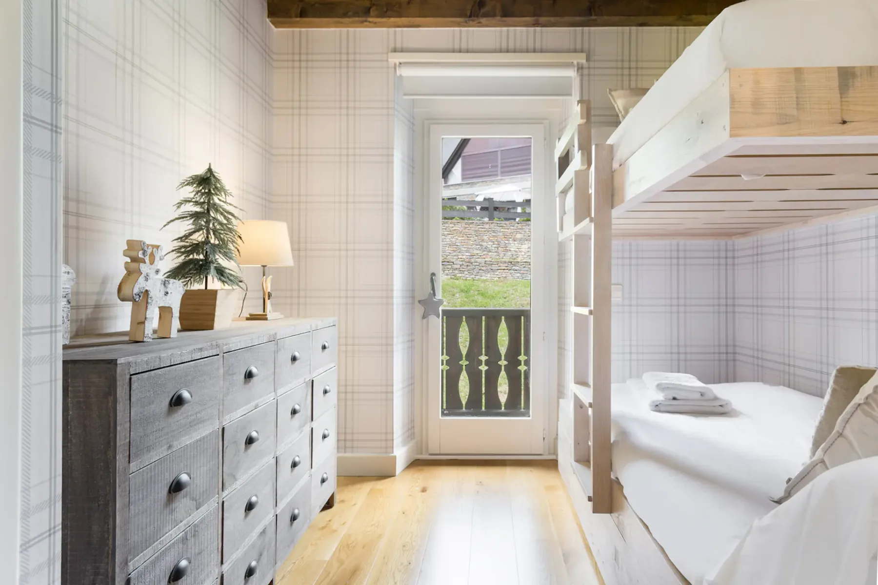 A bright bedroom with bunk beds and a glass door opening onto a small balcony.