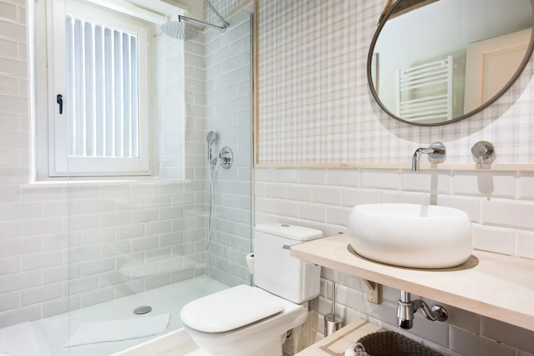 A tiled bathroom with a glass shower area, a toilet, and a vessel sink on a wood-toned counter.