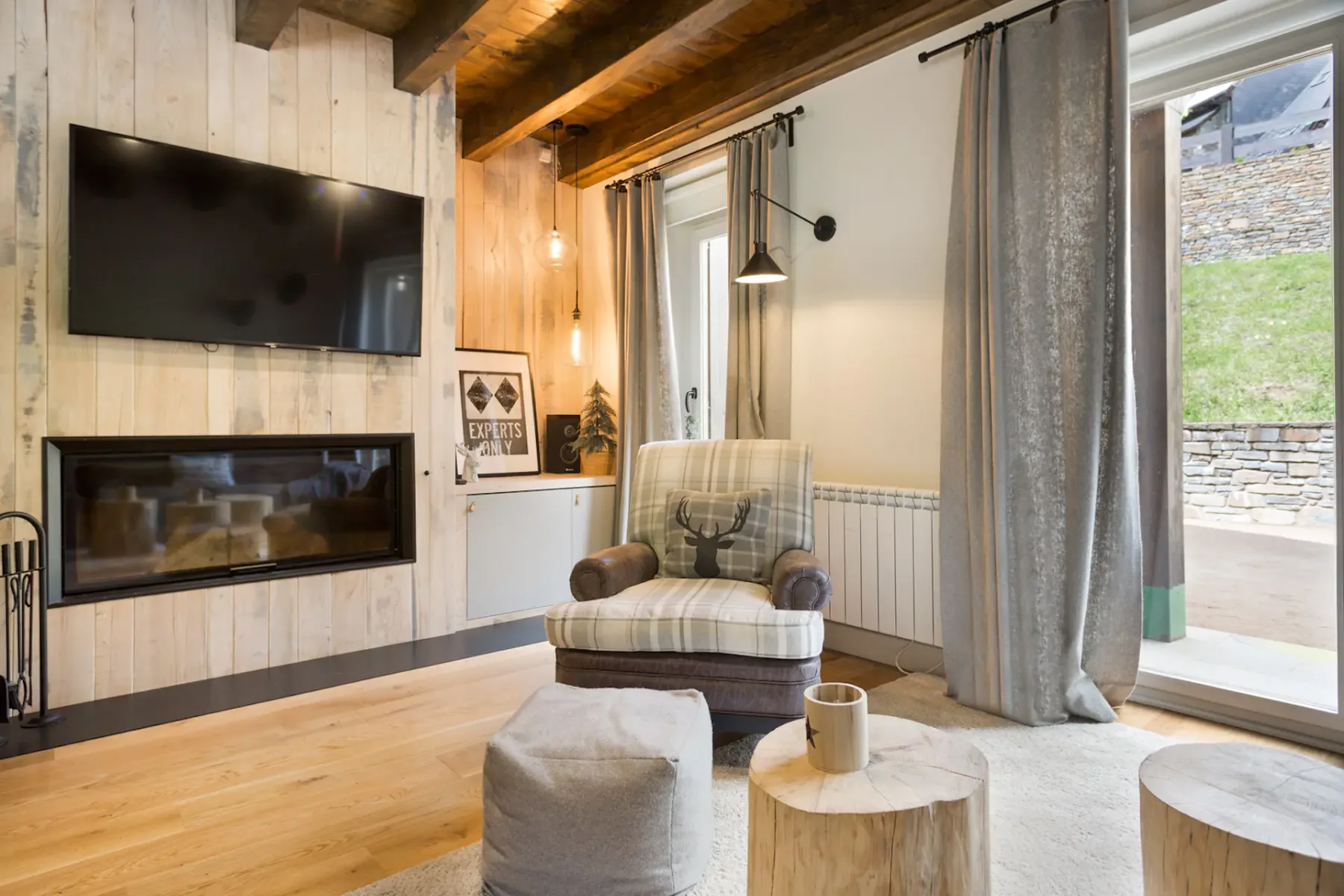 A living area with a plaid armchair, a television, and a glass door opening onto a patio.