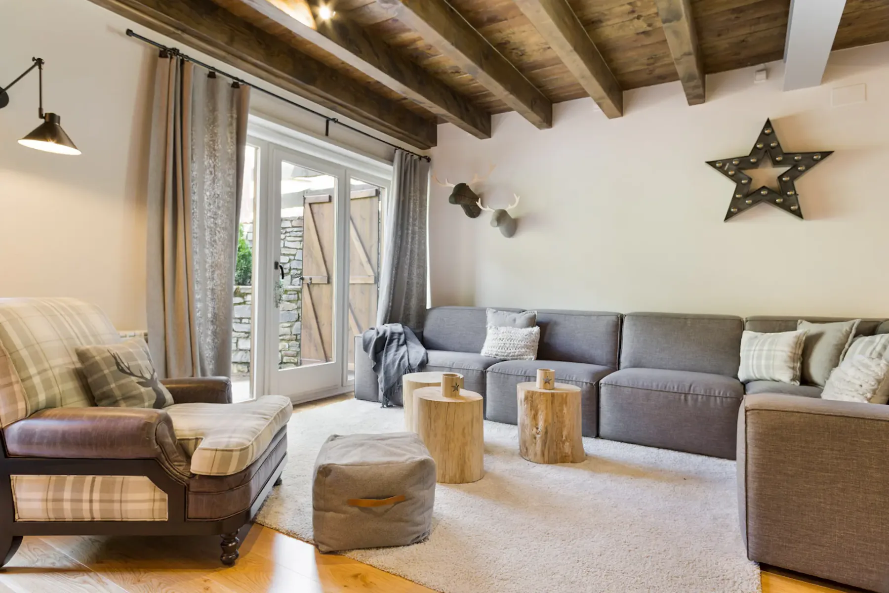 A living room with seating around a rug and exposed wooden ceiling beams.
