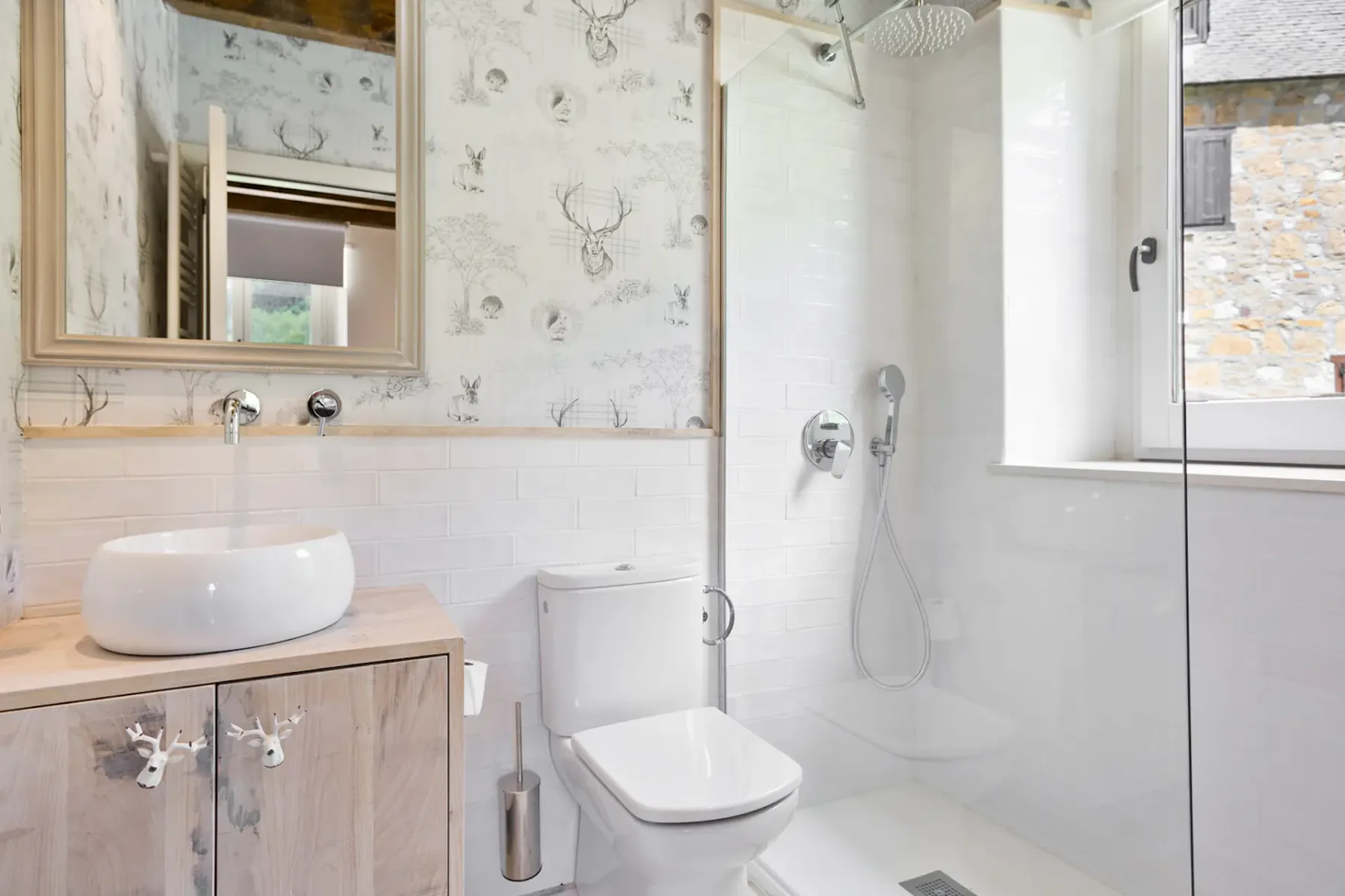 A bright bathroom with a sink, toilet, and glass shower.
