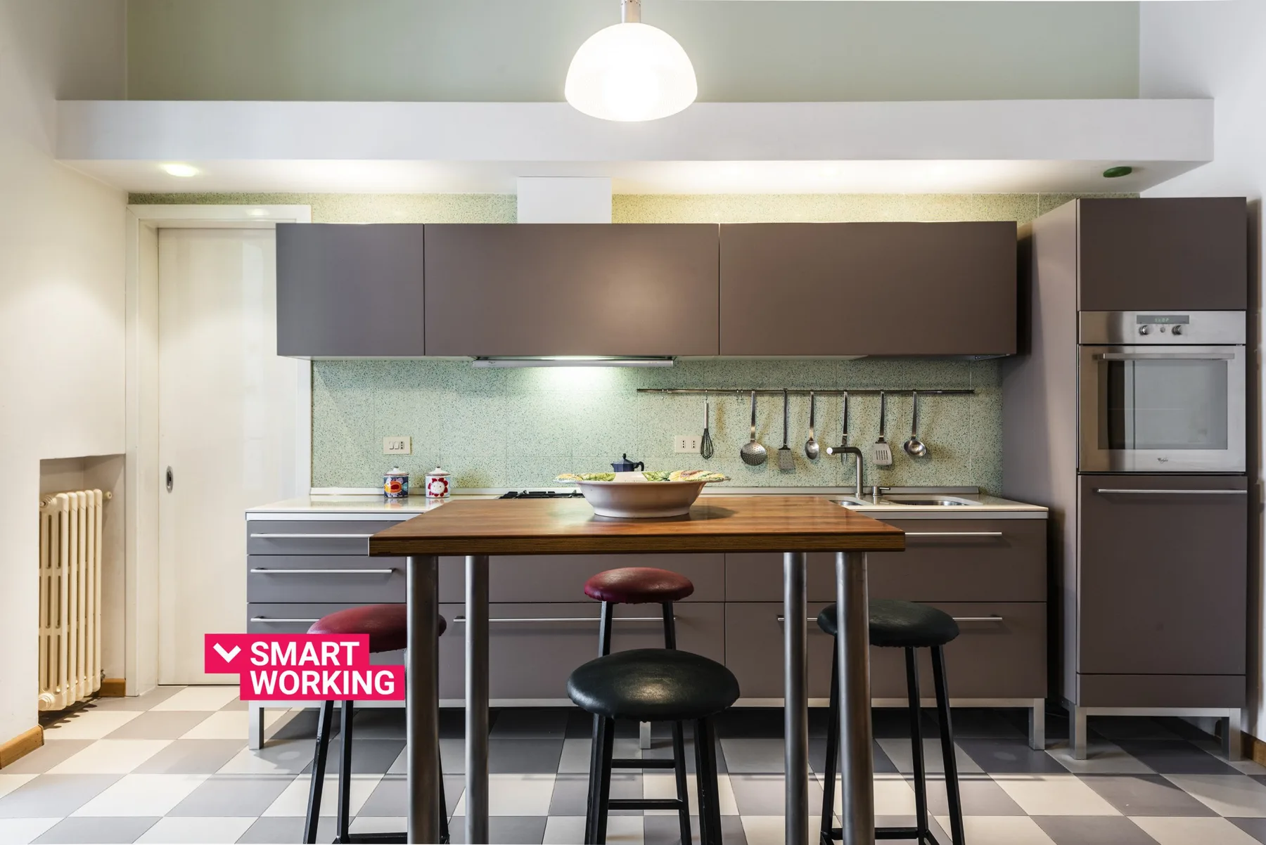 Una cocina moderna con armarios oscuros, una isla central y asientos altos.