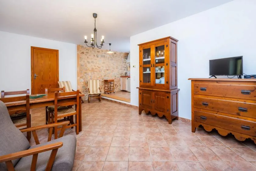 A dining and living area with wooden furniture and a stone accent wall.