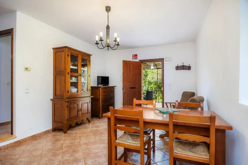 A dining room with a wooden table and chairs, with a cabinet and television nearby.