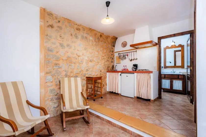 A kitchen and dining area with a small counter, sink, and striped seating.