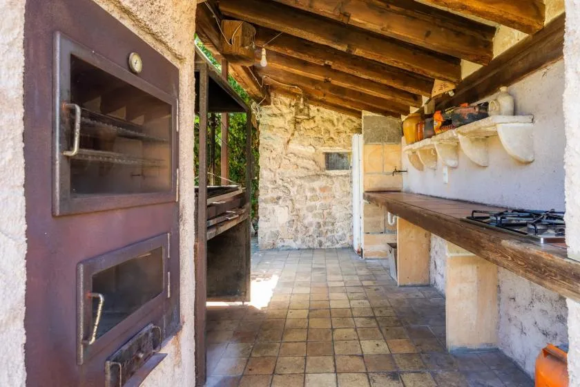 A rustic kitchen with a tiled floor, stone walls, and a long counter.