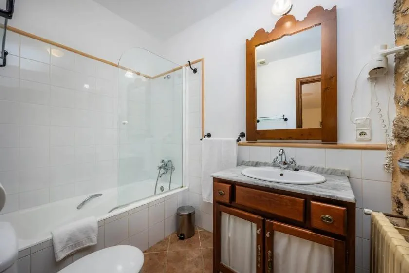 A bathroom with a bathtub and a wooden vanity beneath a mirror.