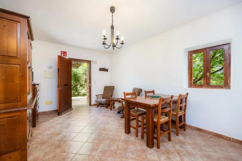 A dining area with a wooden table and chairs beside an open door.