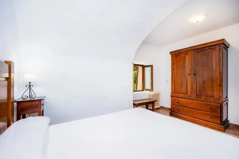 A bedroom with a white bed and a large wooden wardrobe.