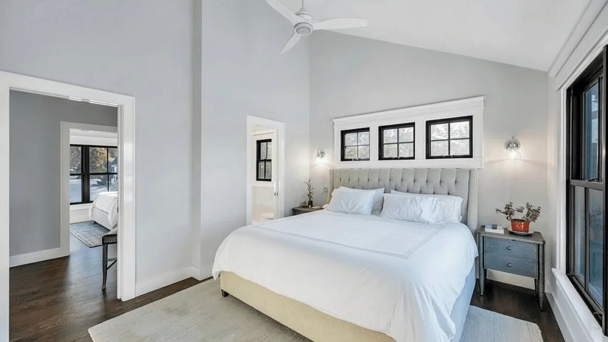 Un dormitorio luminoso con una cama grande y ventanas sobre el cabecero.