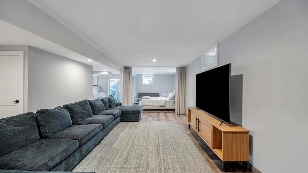 Una sala de estar con una amplia zona de asientos, una alfombra y un televisor.