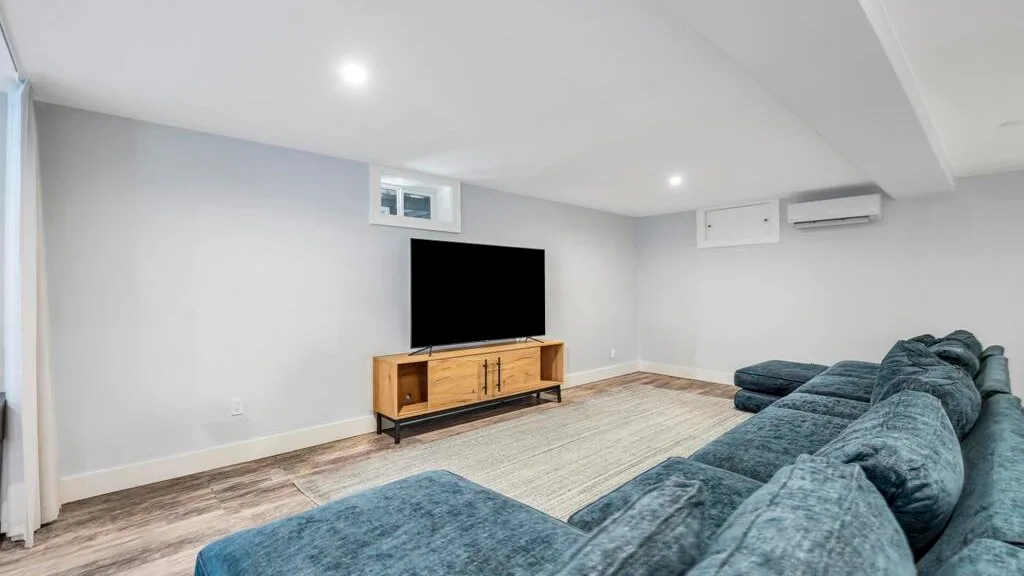 Una sala de estar con un televisor y asientos azules.