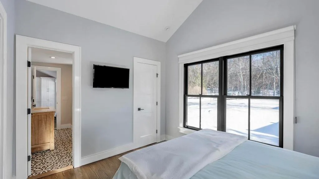 Un dormitorio luminoso con una cama y grandes ventanas con vistas a un paisaje nevado.