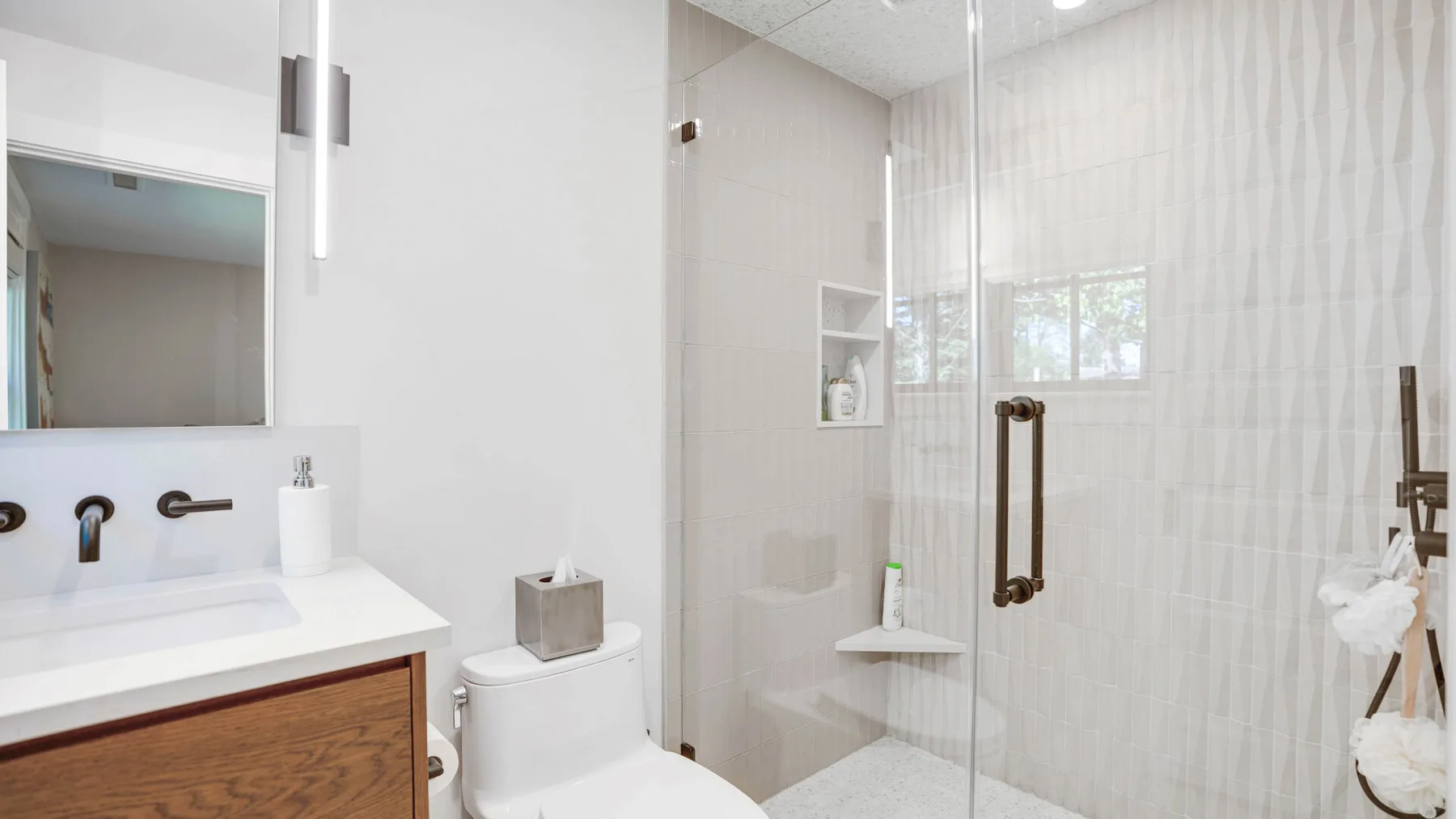 A bright bathroom with a sink, toilet, and glass shower.