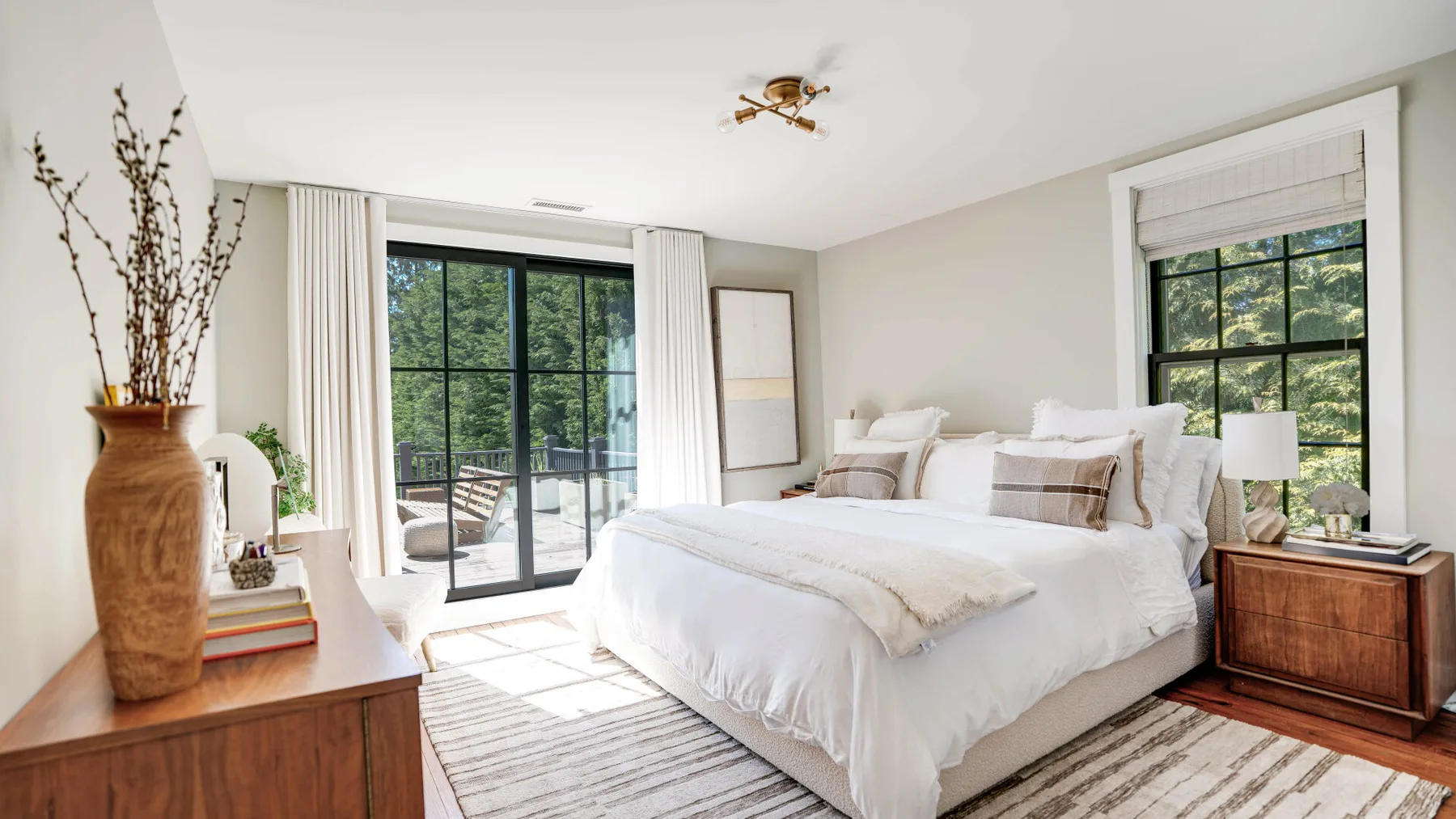 A bright bedroom with a large bed and windows overlooking greenery.