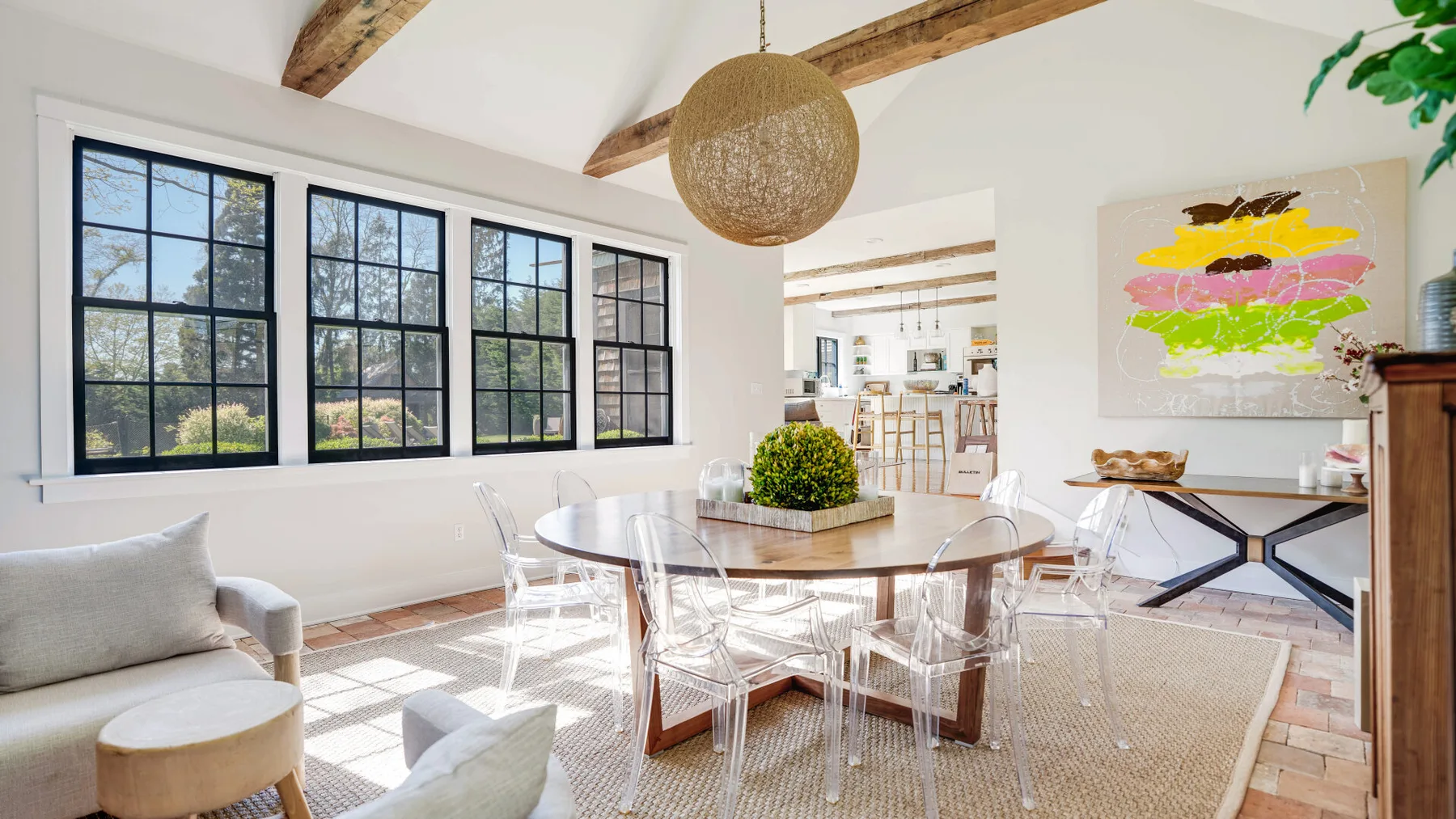 A bright dining area with a round table, clear seating, and large windows.