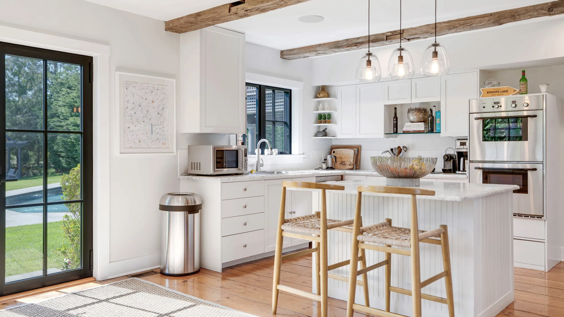 A bright kitchen with a central island and wooden bar stools.