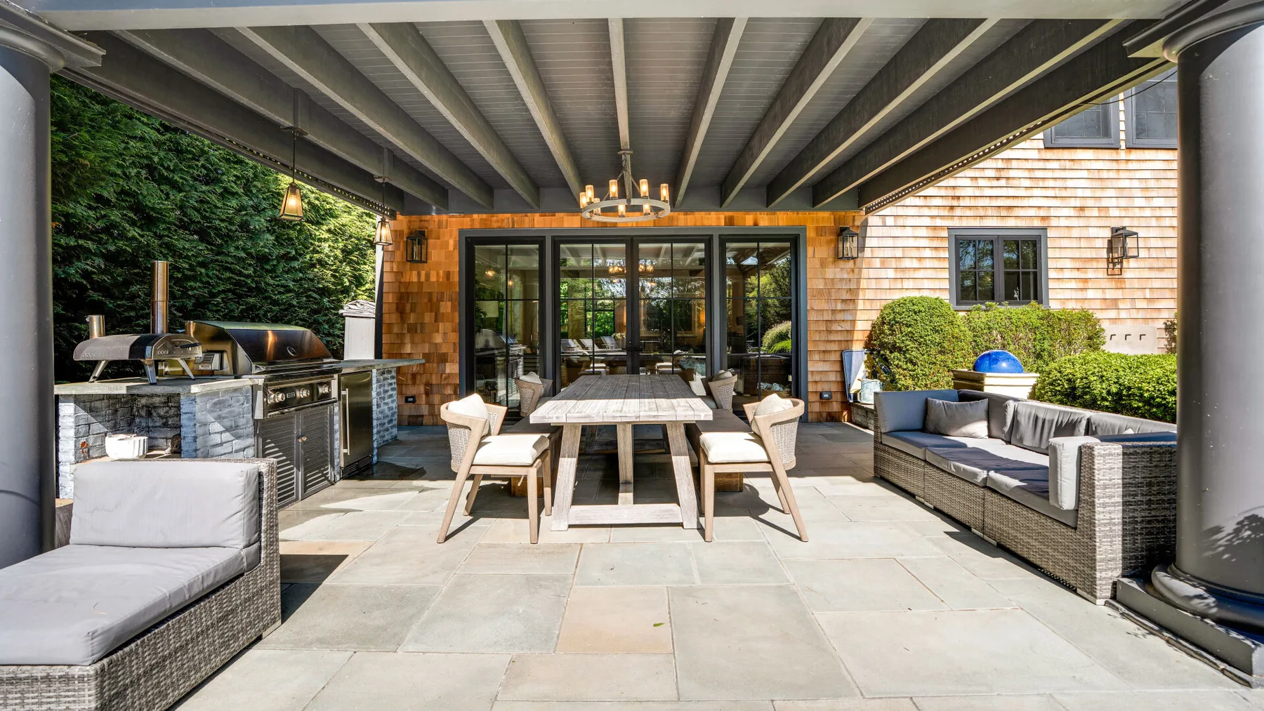 A covered outdoor patio with a dining table and lounge seating.