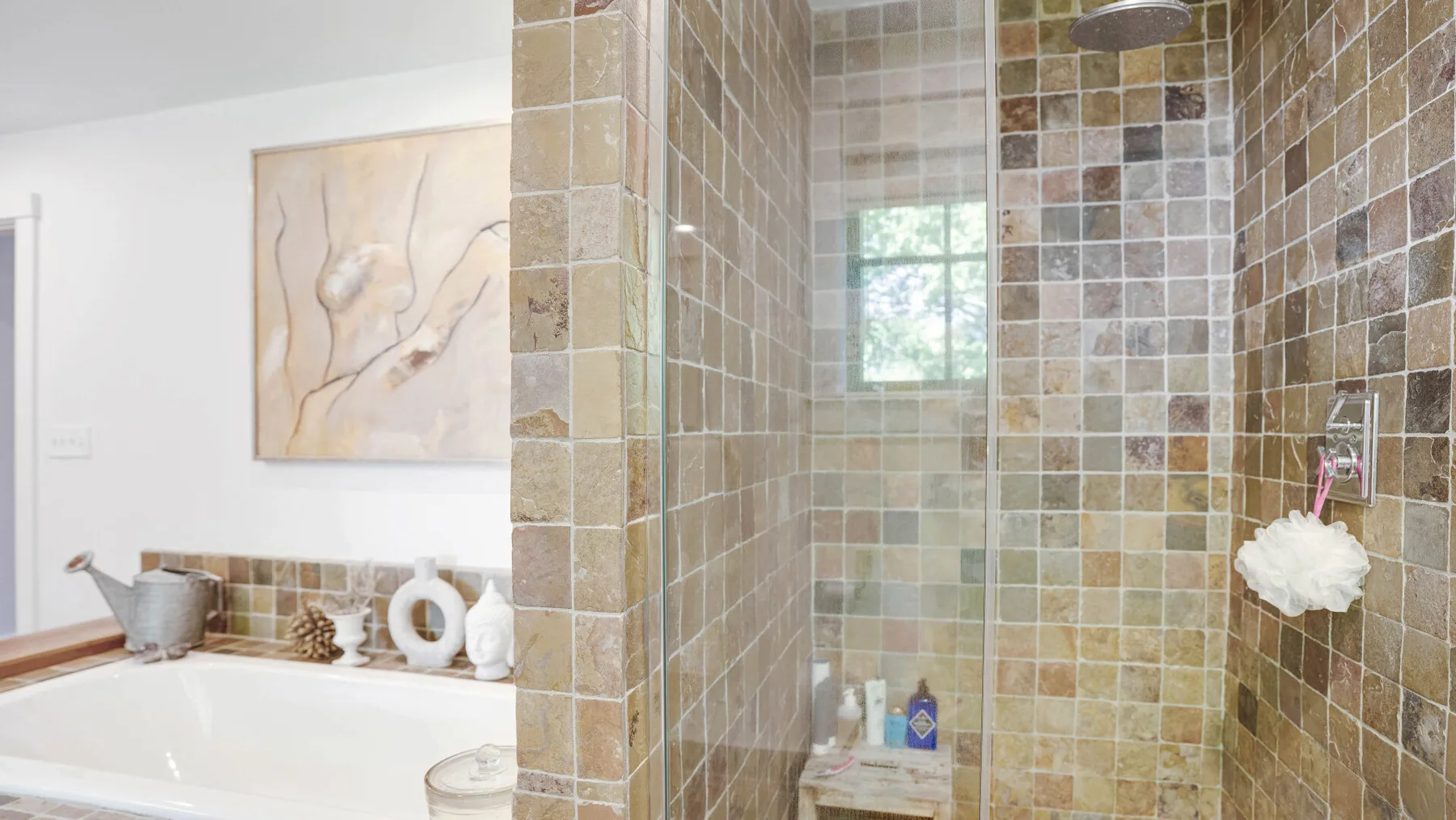 A tiled bathroom with a bathtub beside a glass-enclosed shower.