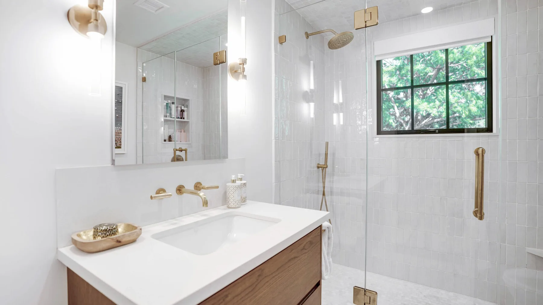 A bright bathroom with a white vanity and a glass shower.