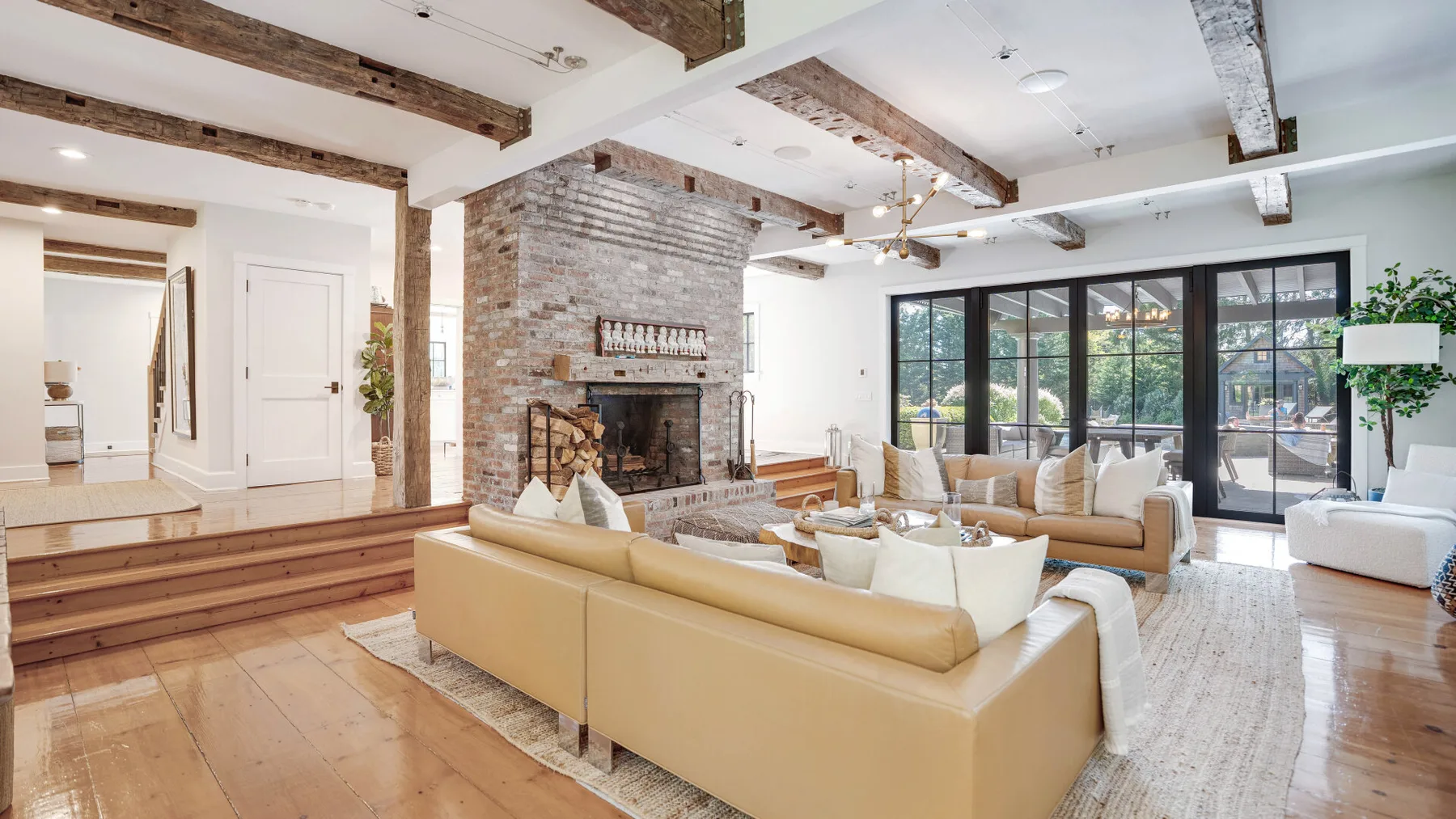 A bright living room with seating arranged around a brick fireplace and large windows.
