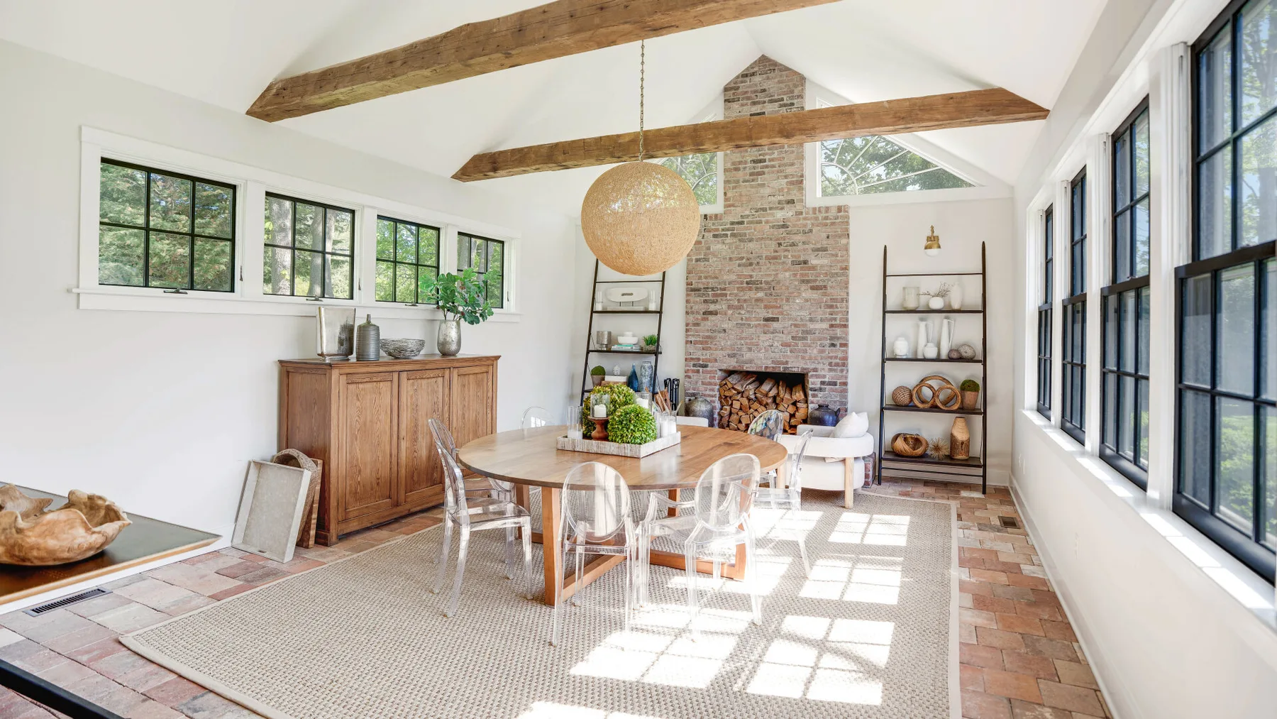 A bright dining room with a wooden table beneath exposed ceiling beams.