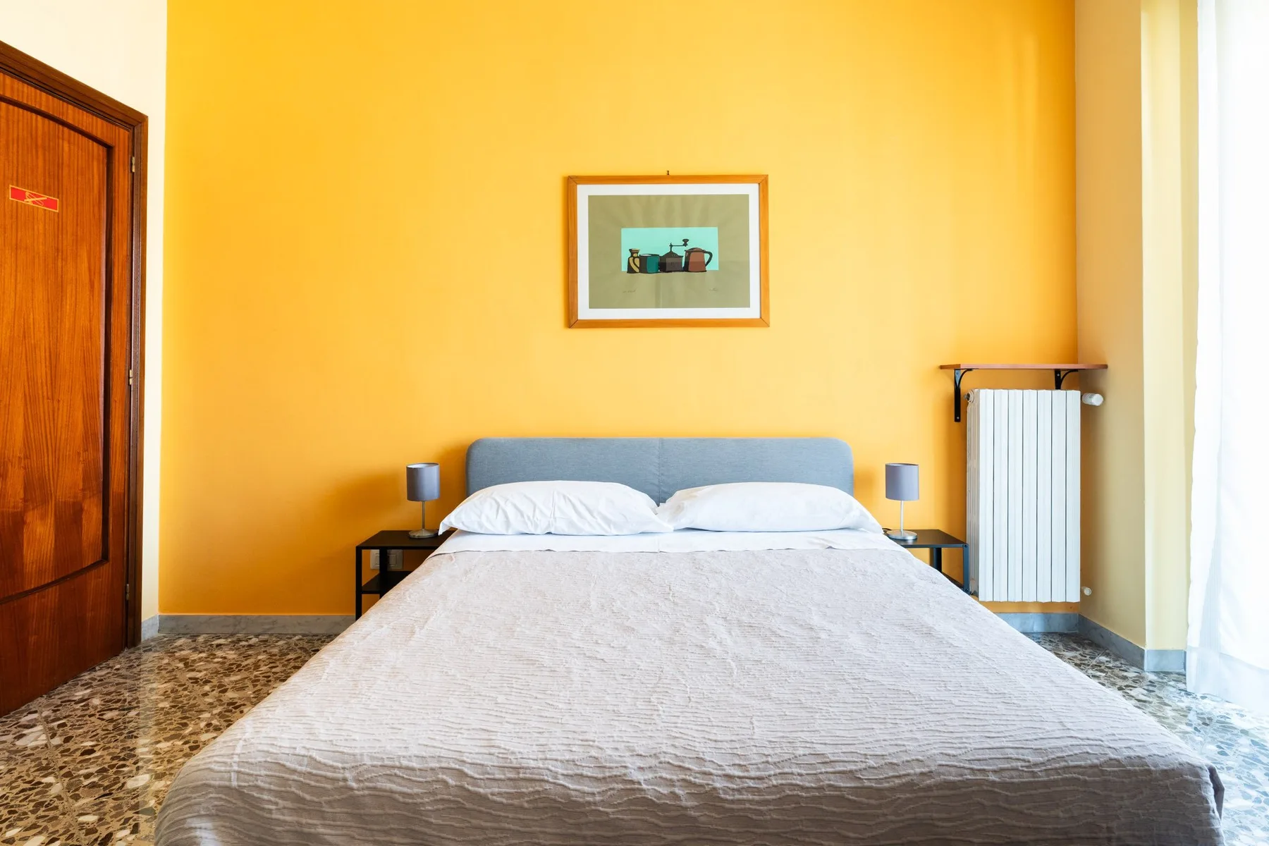 Un dormitorio con una cama doble frente a una pared amarilla.