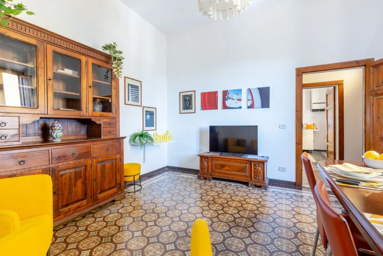 A living room with a wooden cabinet, television, and patterned tile floor.