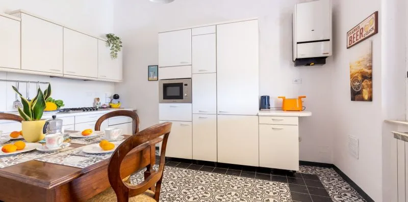 A bright kitchen and dining area with white cabinets and a wooden table.