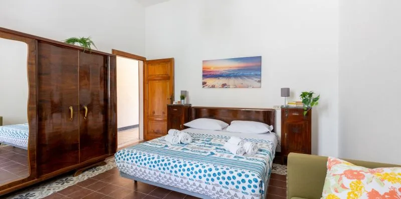 Un dormitorio con una cama doble, armarios de madera y una colorida imagen de playa.