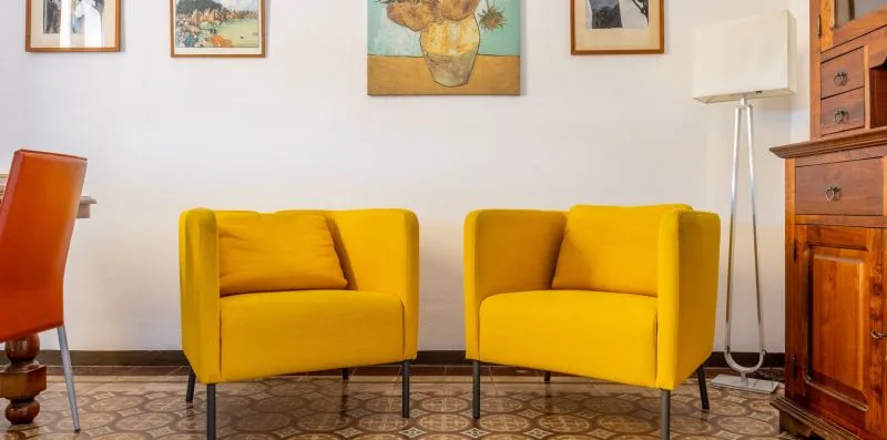 A living room with yellow seating and framed artwork on the wall.