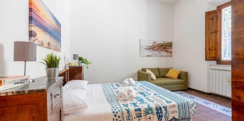 A bright bedroom with a patterned bedspread and a green sofa.