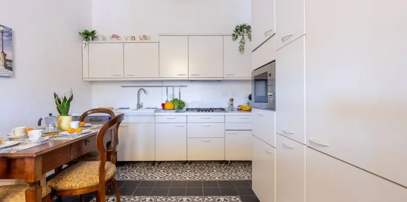 A bright kitchen with white cabinets, a countertop, and a dining table.