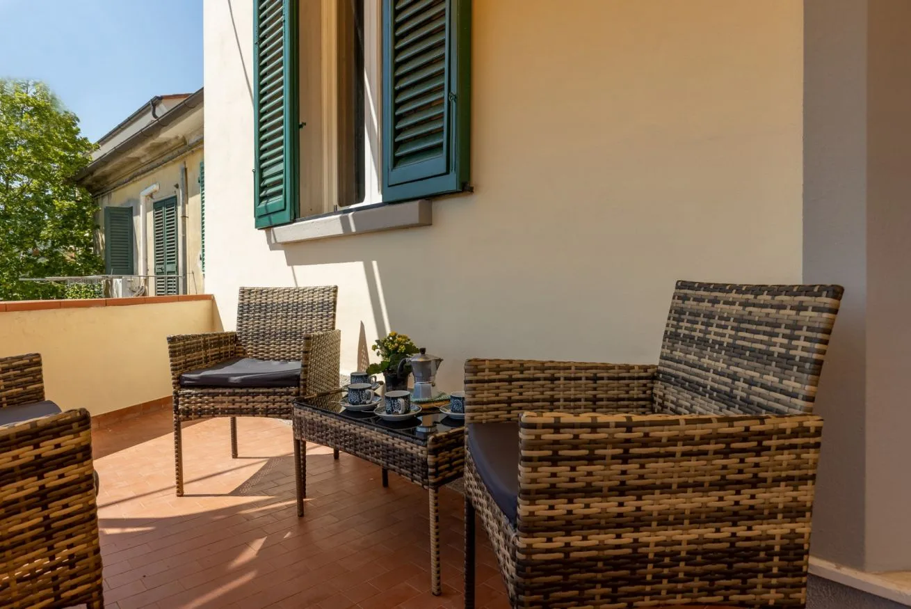 A sunny terrace with woven seating and green shutters on the wall.