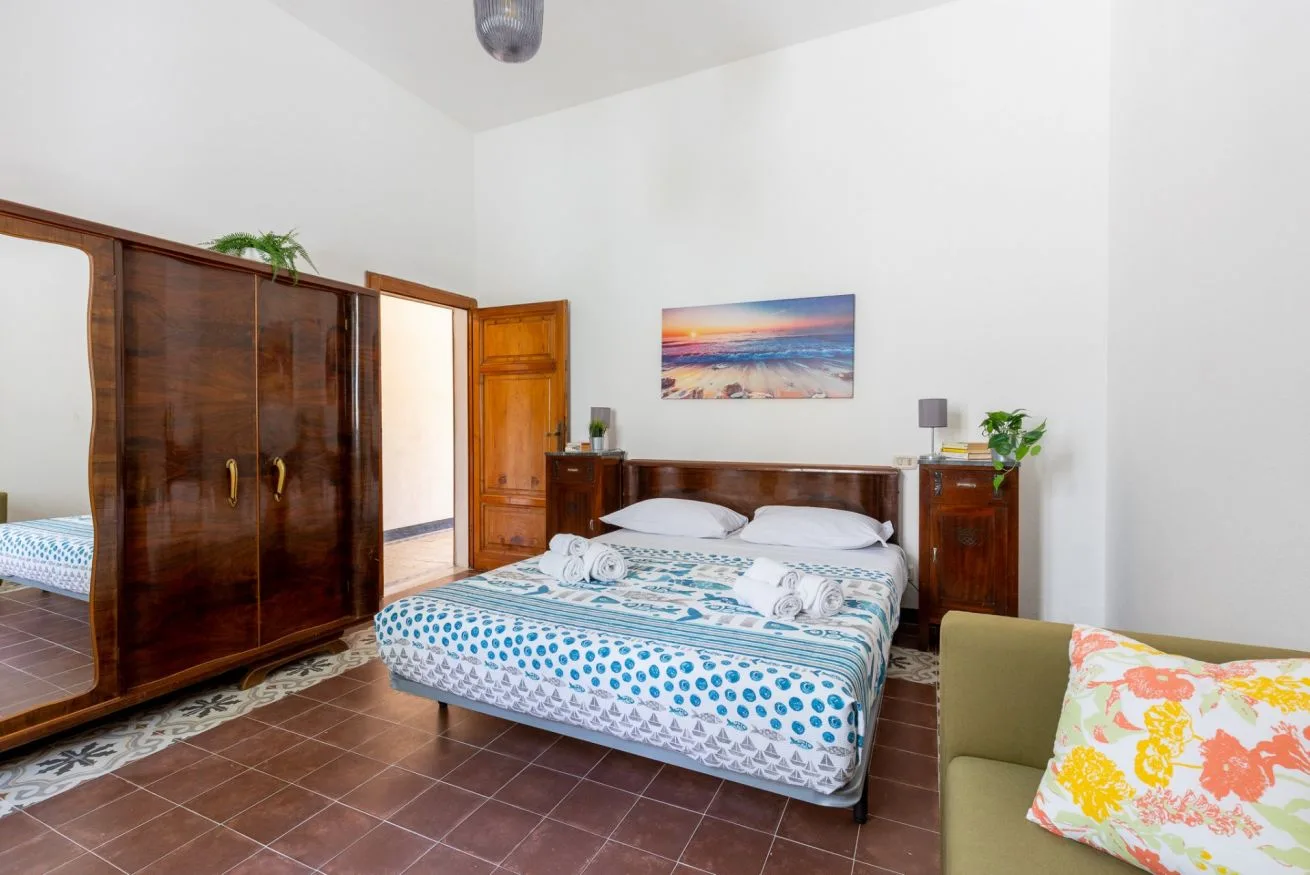 A bedroom with a double bed, wooden wardrobe, and colorful bedding.
